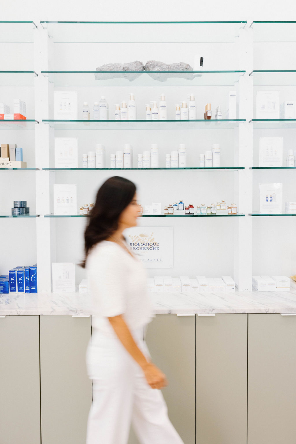 Skincare products on glass shelving in a bright clinic retail space